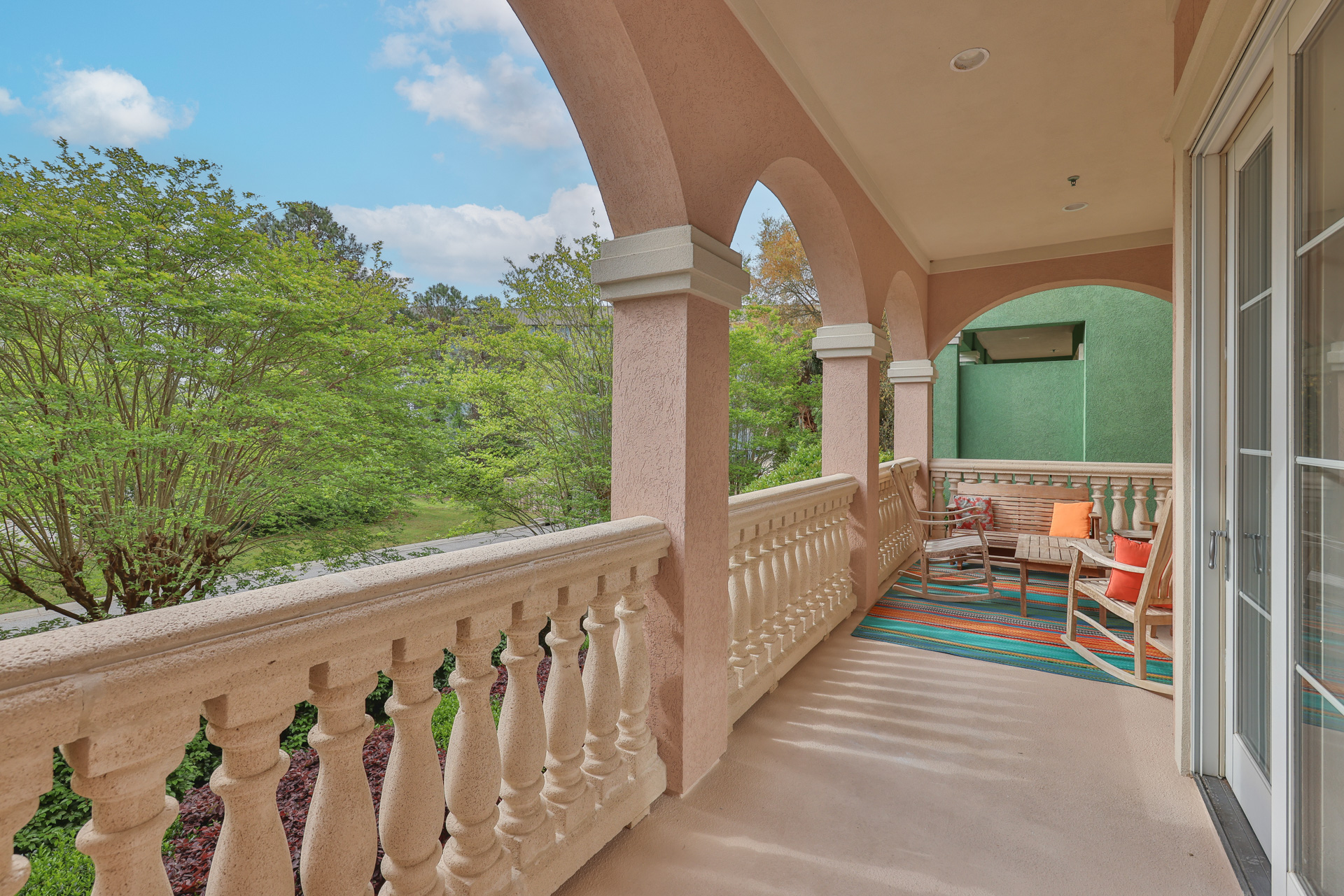Lower balcony with arched columns, seating and garden views