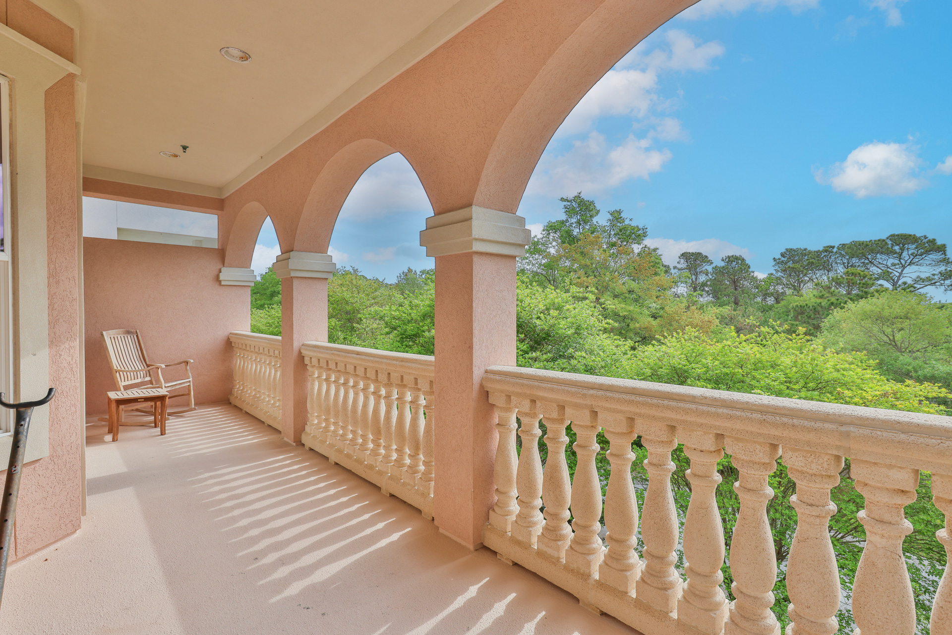 Upper arched balcony with blue sky and treetop views