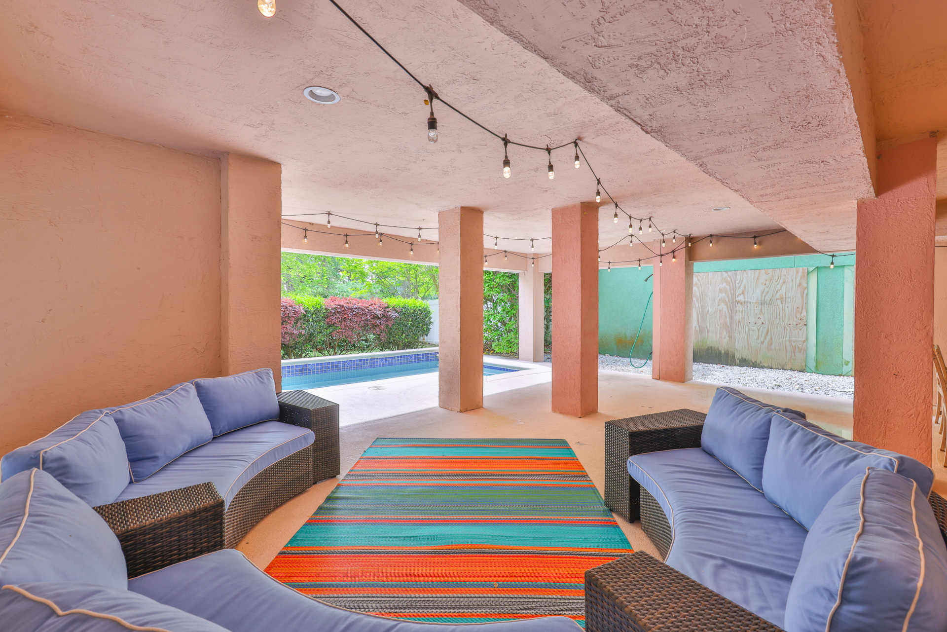 Covered patio with blue sofas opening to the pool