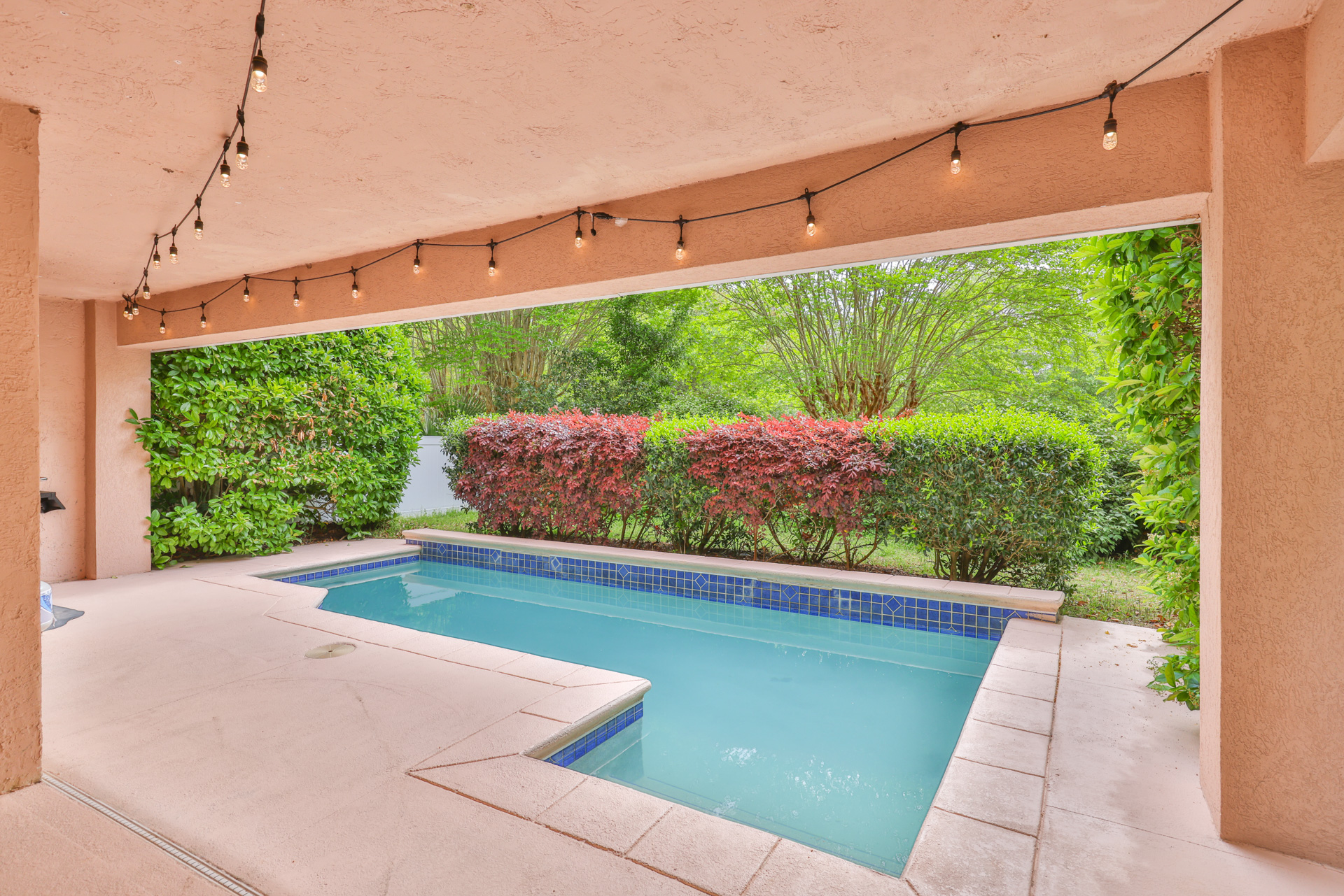 Private heated pool framed by string lights and lush garden